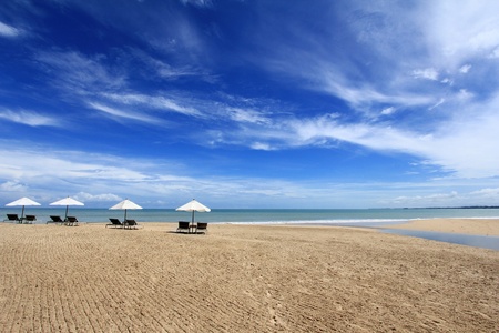 Sunbathing Beds with White Umbrella along the tropical beachの写真素材