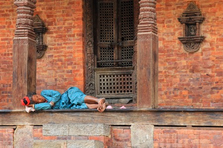 KATHMANDU, NEPAL - APRIL 2014 : A Nepalese woman resting at the temple at Kathmandu Durbar Square in Kathmandu, Nepal on 12 April 2014.のeditorial素材
