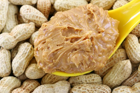 A spoon of creamy crunchy peanut butter on peanuts