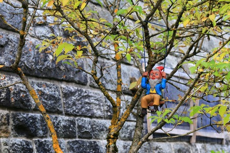 A small Dwarf figure sitting on a swing used to decorate a tree in the gardenの写真素材