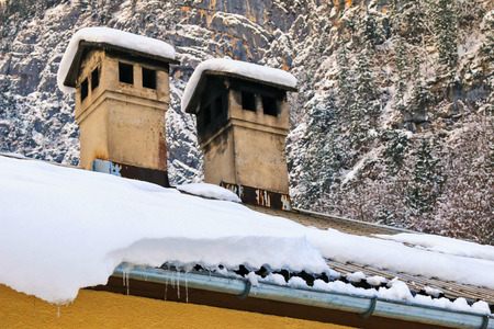Old styled chimneys with black soot being covered with snow during Winter seasonの写真素材