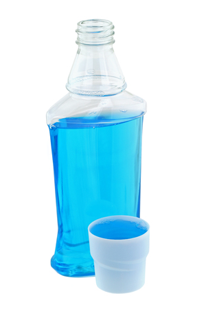 A cap full of light blue post brush antiseptic mouthwash liquid next to its bottle, isolated on whiteの写真素材
