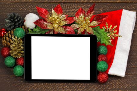 A black tablet computer with blank white screen on top of glittery Christmas decoration on brown wooden backgroundの写真素材