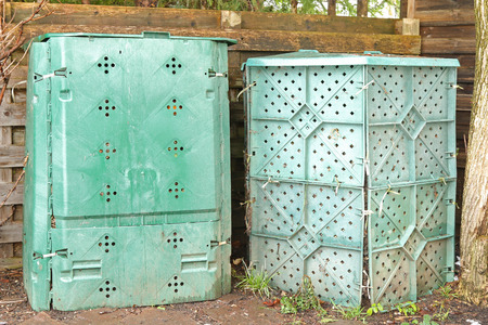 Big compost plastic boxes in green full of biodegradable organic and food scraps in the backyard for...