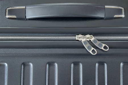 Closeup top view of silver zipper of hard shelled suitcase, new and clean luggage in black color...