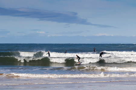 TORQUAY, AUSTRALIA - APRIL, 2016 : Paddlers in black drysuits doing the stand up paddling at Torquay...