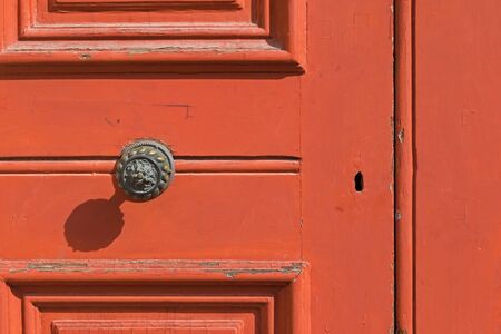 Closeup background of red wooden door with keyhole, brass doorknob with shadowの写真素材