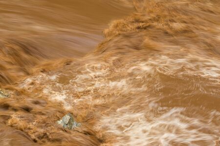 Closeup of rapid flow of brown water in the muddy river during rainy season, slow motion photoの写真素材