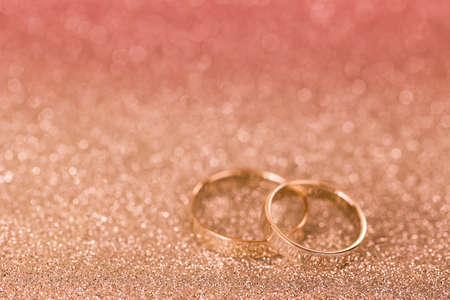 Soft focus of 2 silver rings on glittery background, shallow depth of field with pink filter and copyspaceの写真素材