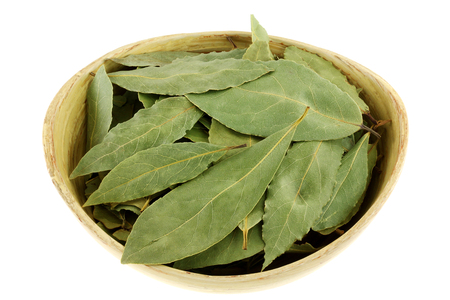 Dried Bay leaves in a wooden bowl isolated on white backgroundの写真素材