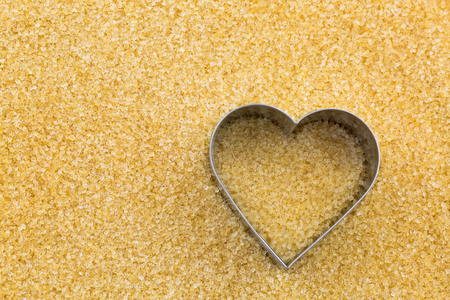Top view of Metal heart shaped cookie cutter on unrefined unbleached Crystalline sugar in crystal brown color with copyspace. Conceptual photo for sweet love
の写真素材