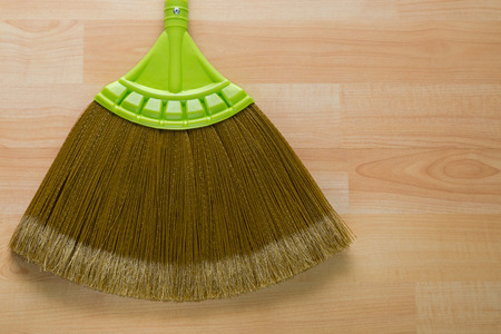 Closeup of new broom made of synthetic Nylon fiber with green handle on wooden background with copyspace
の写真素材