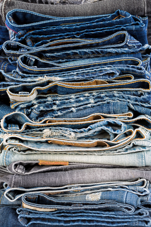Closeup stack of folded clothes, blue jeans pants texture, dark blue denim trousers showing waistbands
の写真素材
