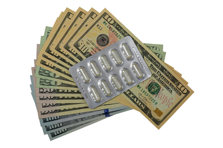 Package of herbal medicine in clear capsules on American dollar banknote money isolated on whiteの写真素材