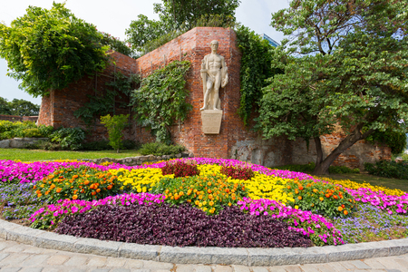 GRAZ, AUSTRIA - JULY 2018 : Sculpture titled Furchtlos und treu INF.RGT.27 - 1682-1918, meaning Fearless and faithful, on fortress wall above colorful flower bed at Schlossberg Castle Hill in Graz, Austria on July 20, 2018.のeditorial素材