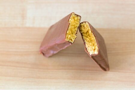 Chocolate coated peanut butter Energy bar with protein blend, amino acids broke into half on wooden backgroundの写真素材