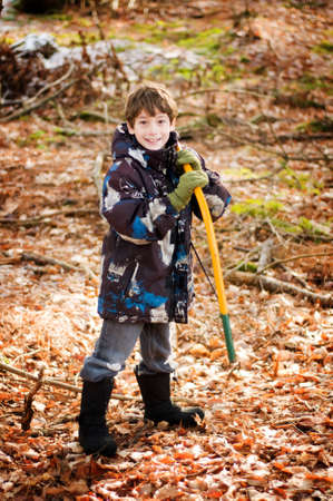young boy with a saw to help cut down a christmas treeの写真素材
