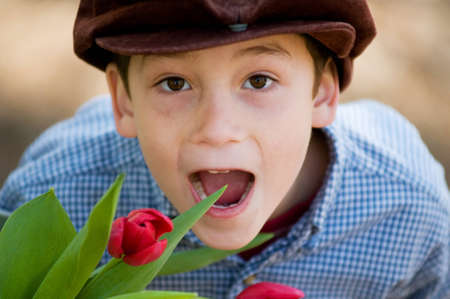 adorable boy outdoors in a sprintime forest with a bucket full of colourful tulips