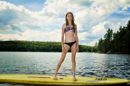 teen girl standing on a paddle board floating in the lakeの写真素材