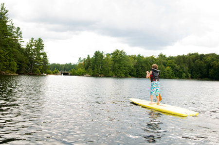 young boy stand up paddle boardingの写真素材