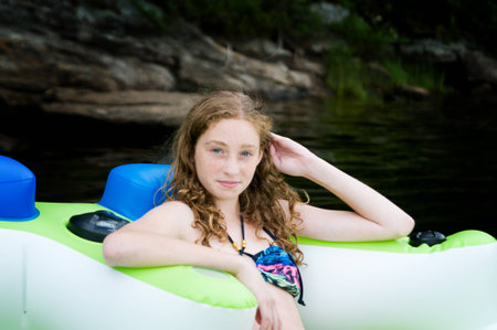 pretty teen girl floating in an inflatable raft on a lake in haliburton ontarioの写真素材