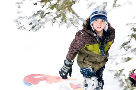 young boy outdoors in winter clothing playing in the snowの写真素材