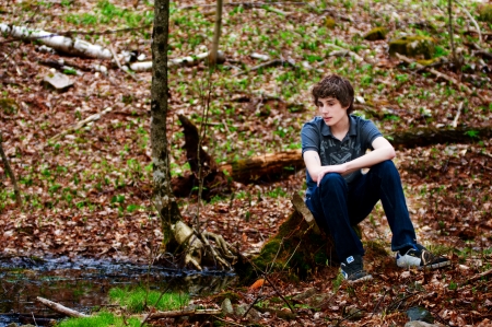 teen boy sitting in a forestの写真素材