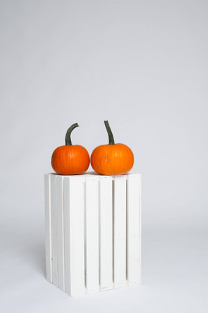 two bright orange pumpkins on a white crateの写真素材