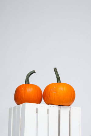 two bright orange pumpkins on a white crate