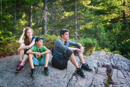 three siblings enjoying the view from atop a nature hike lookoutの写真素材