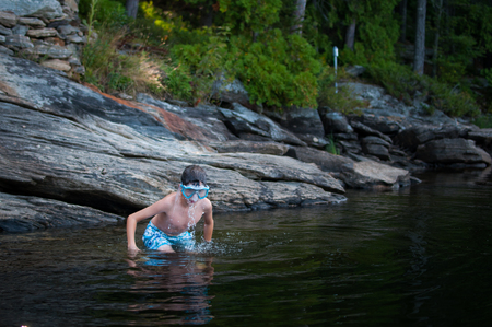 child playing in a lake wearing swim goggles in summertimeの写真素材