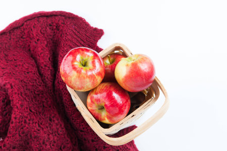 backet of red apples and a warm wool blanket on a white backgroundの写真素材