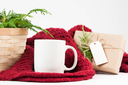 coffee mug mockup with basket of greenery, red blanket and brown papper wrapped giftの写真素材