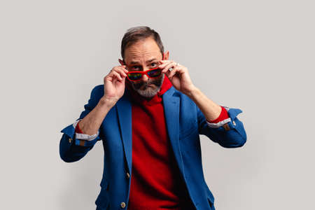 Stylish senior man peeking through sunglasses