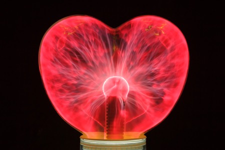 Plasma ball heart glowing in the dark isolated on black