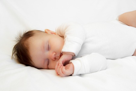 Little newborn girl slepping on a white backgroundの写真素材
