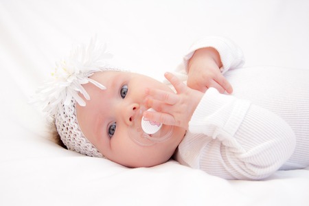Little newborn girl lying on the bed on a white background
