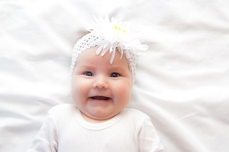 Little newborn girl lying on the bed on a white backgroundの写真素材