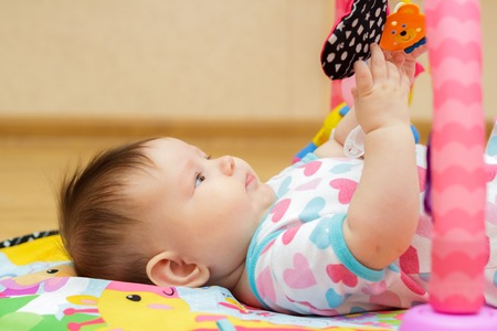 Happy little newborn baby with toys on the floorの写真素材