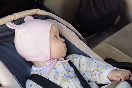 little newborn baby girl rests in the car seat in carの写真素材