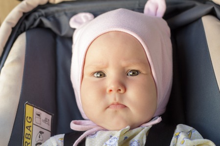 little newborn baby girl rests in the car seat in car