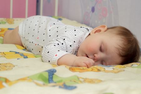 Little newborn baby girl sleeping on a big bedの写真素材