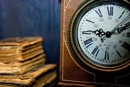 Old books and old clock with leather coverの写真素材