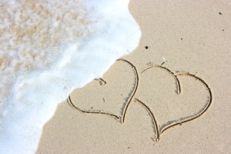 Two hearts drawing on the sandy beachの写真素材