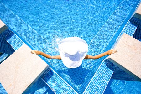 Girl in white hat sitting in the swimming poolの写真素材