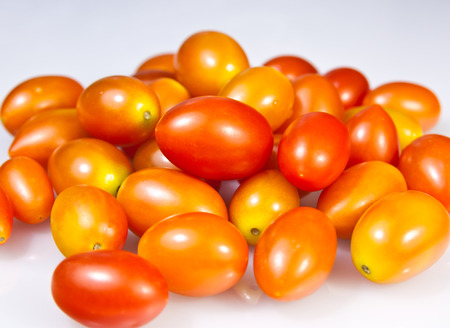 a pile of baby plum tomatoes on a white の写真素材