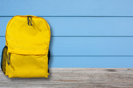 Bag or backpack is placed on a wooden table with blue walls, vintage style.