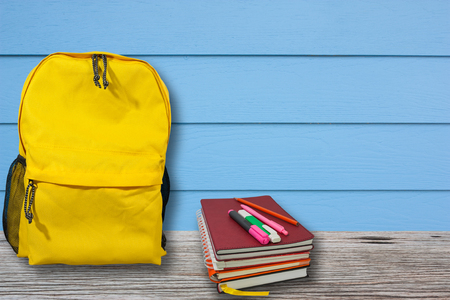 Backpack and notebook is placed on a wooden table with blue wall, Vintage style.の写真素材