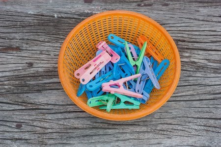 Clothespin clips in a basket placed on a wooden floor.の写真素材