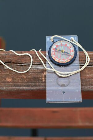 Picture of a compass on the wooden railing of the bridge through the river close-UPS の写真素材